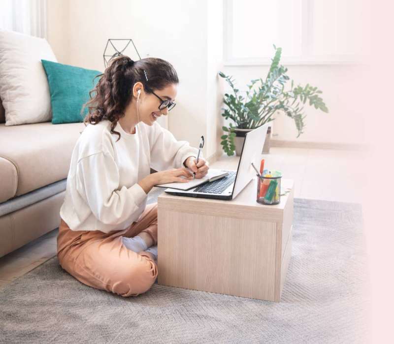 Deutsch Online Kurs: Teilnehmerin lernt am Laptop zuhause und macht Notizen